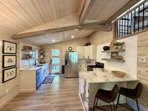 A spacious kitchen with wooden beams, a large island, and a refrigerator. - Among the Pines • Minutes to Sundance (Sundance)