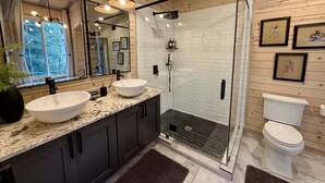 Un bagno moderno con cabina doccia in vetro, mobile lavabo doppio e water.