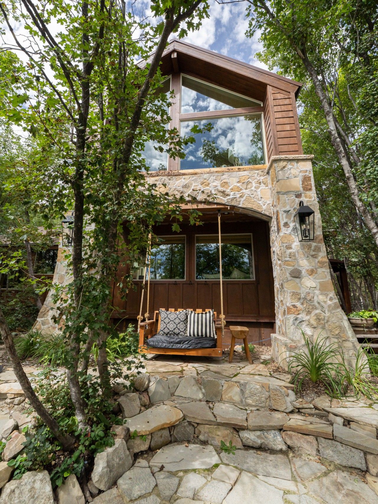 Una casa de piedra con un porche de madera y un columpio.