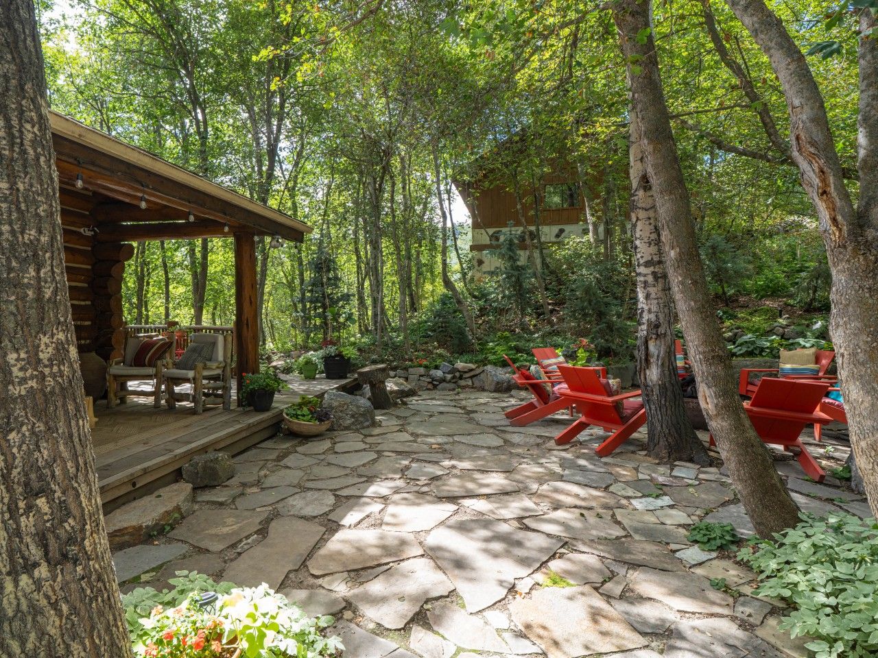 Une terrasse en pierre avec des sièges d’extérieur et une structure en bois.