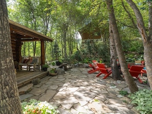 A stone patio with outdoor seating and a wooden structure.