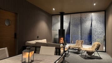 Een modern interieur met een open haard, zithoek en grote ramen.