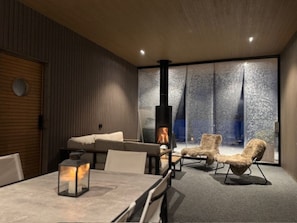 A modern interior with a fireplace, seating area, and large windows.