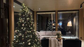Uma sala de estar moderna com uma grande árvore de Natal, um sofá, uma mesa de centro e um abajur.
