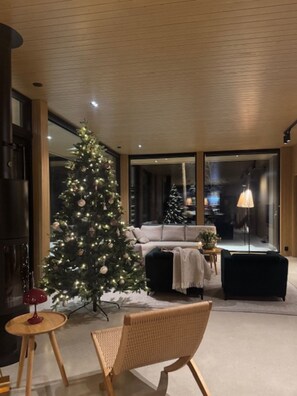 Uma sala de estar moderna com uma grande árvore de Natal, um sofá, uma mesa de centro e um abajur.