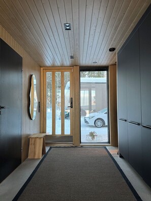 Interior moderno com teto de madeira, porta de correr de vidro para o exterior e guarda-roupa em tons escuros.