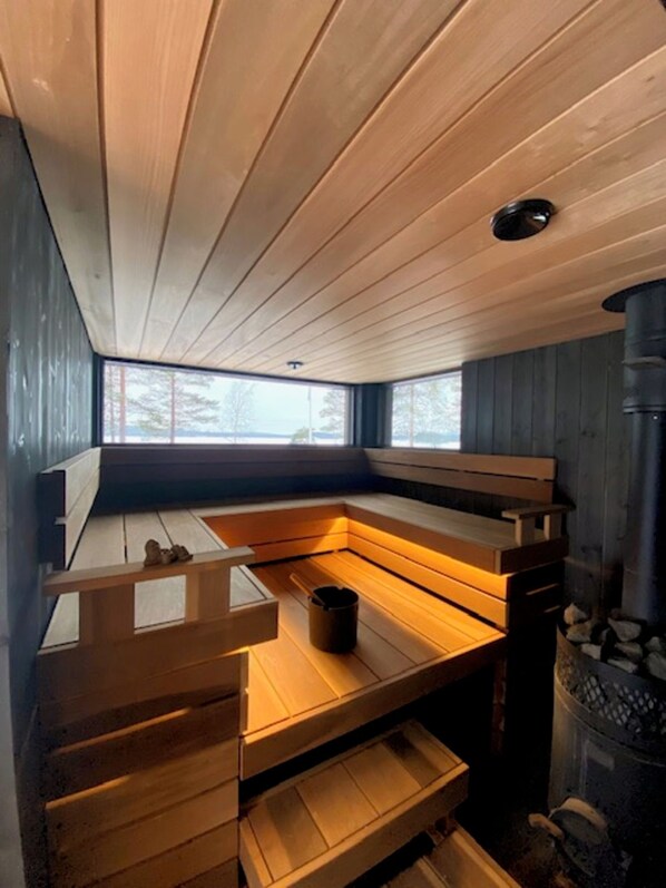 A sauna room with wooden benches and a visible chimney.