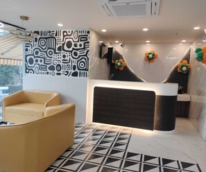 A modern reception area with a patterned wall, a reception desk, a leather chair, and a geometric floor pattern. - Premium Deluxe Room RIO Patna (Patna)