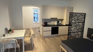 Ett kompakt bostadsutrymme med ett litet kök, en matplats och en säng.