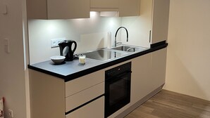 Ett modernt kök med en svart bänkskiva, en diskho i rostfritt stål och en inbyggd ugn.