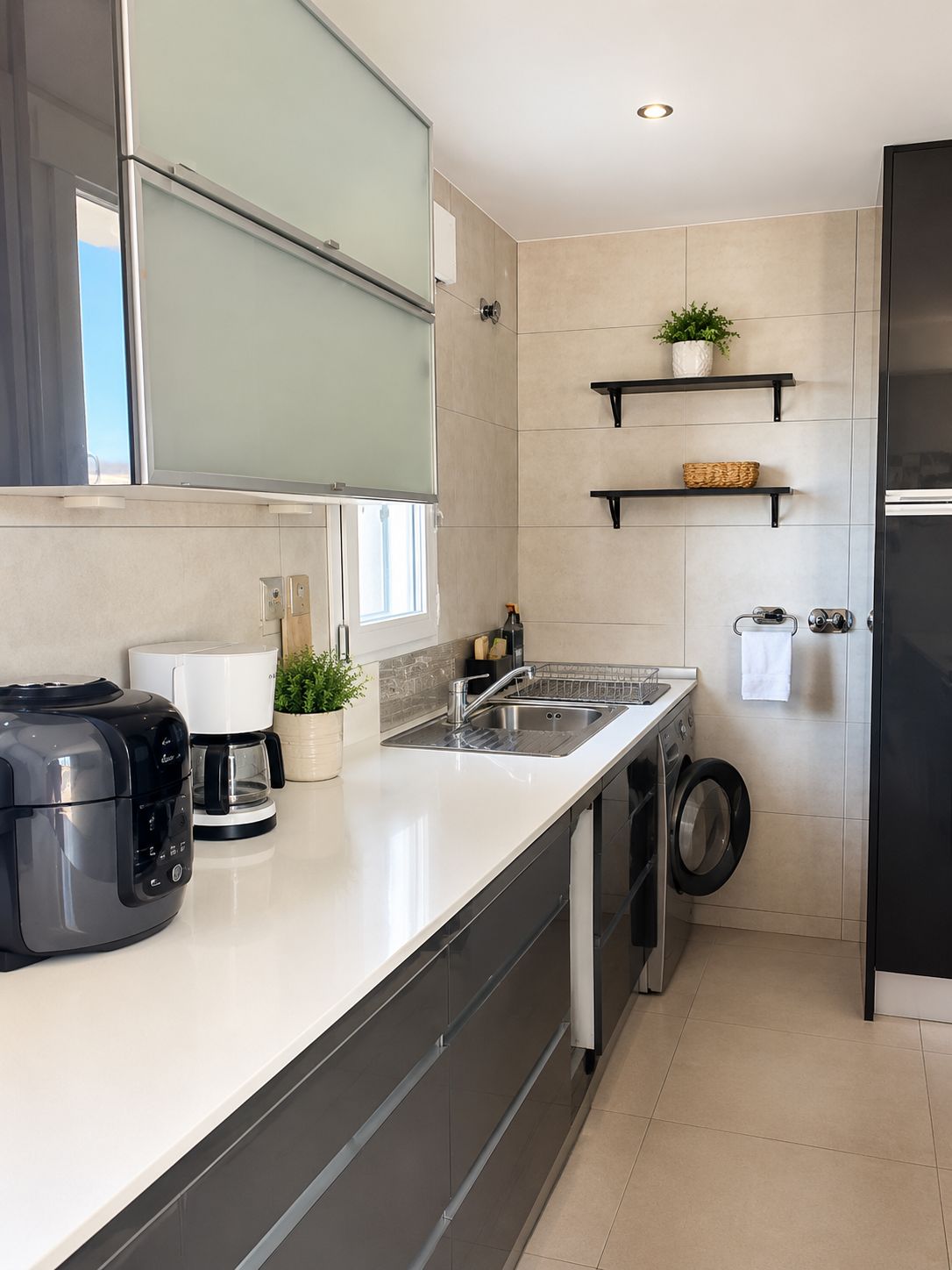 Eine moderne Küche mit Backofen, Kaffeemaschine, Spüle und Waschmaschine.
