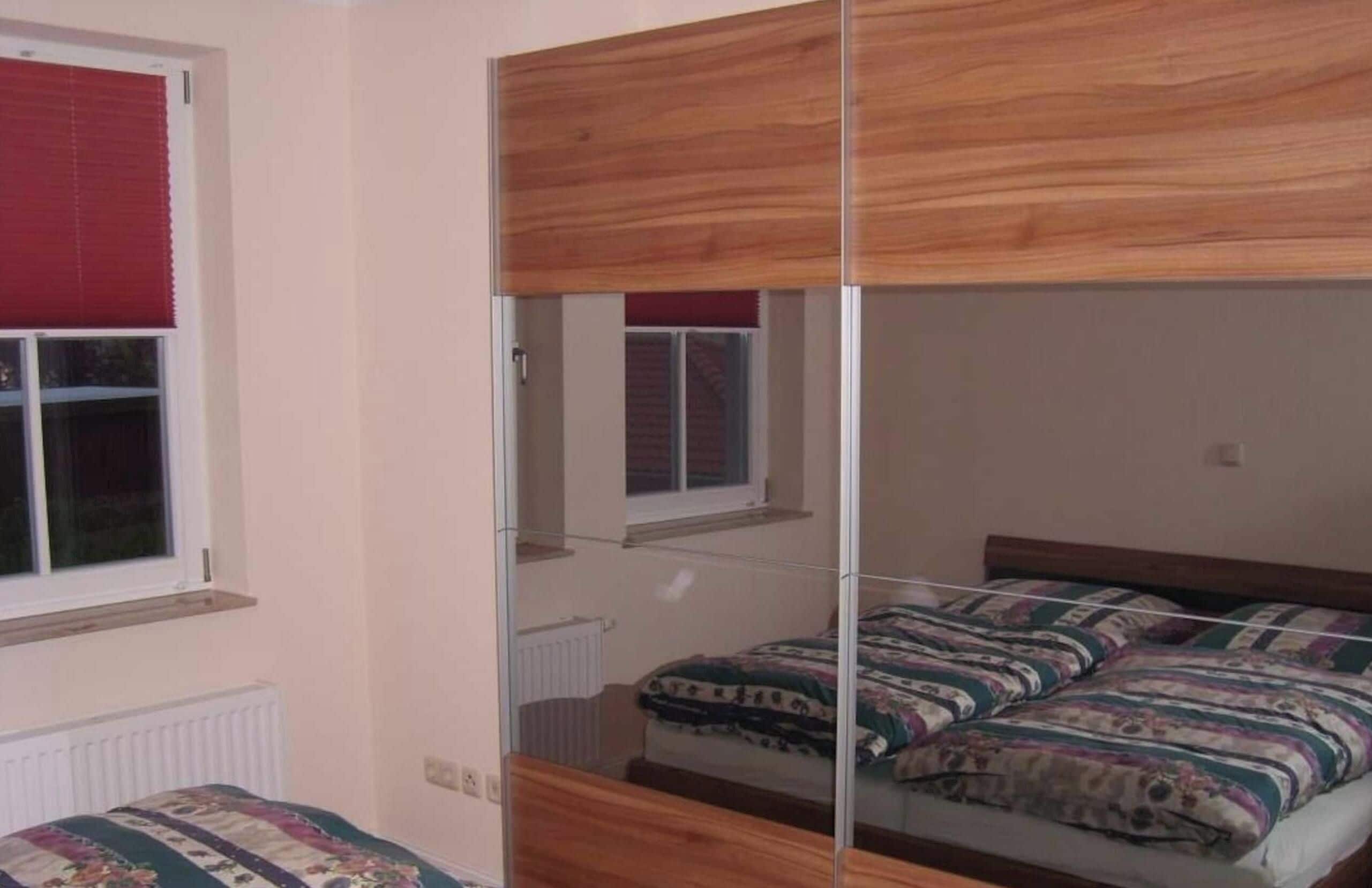A room with a bunk bed, a window with a red blind, and a radiator.