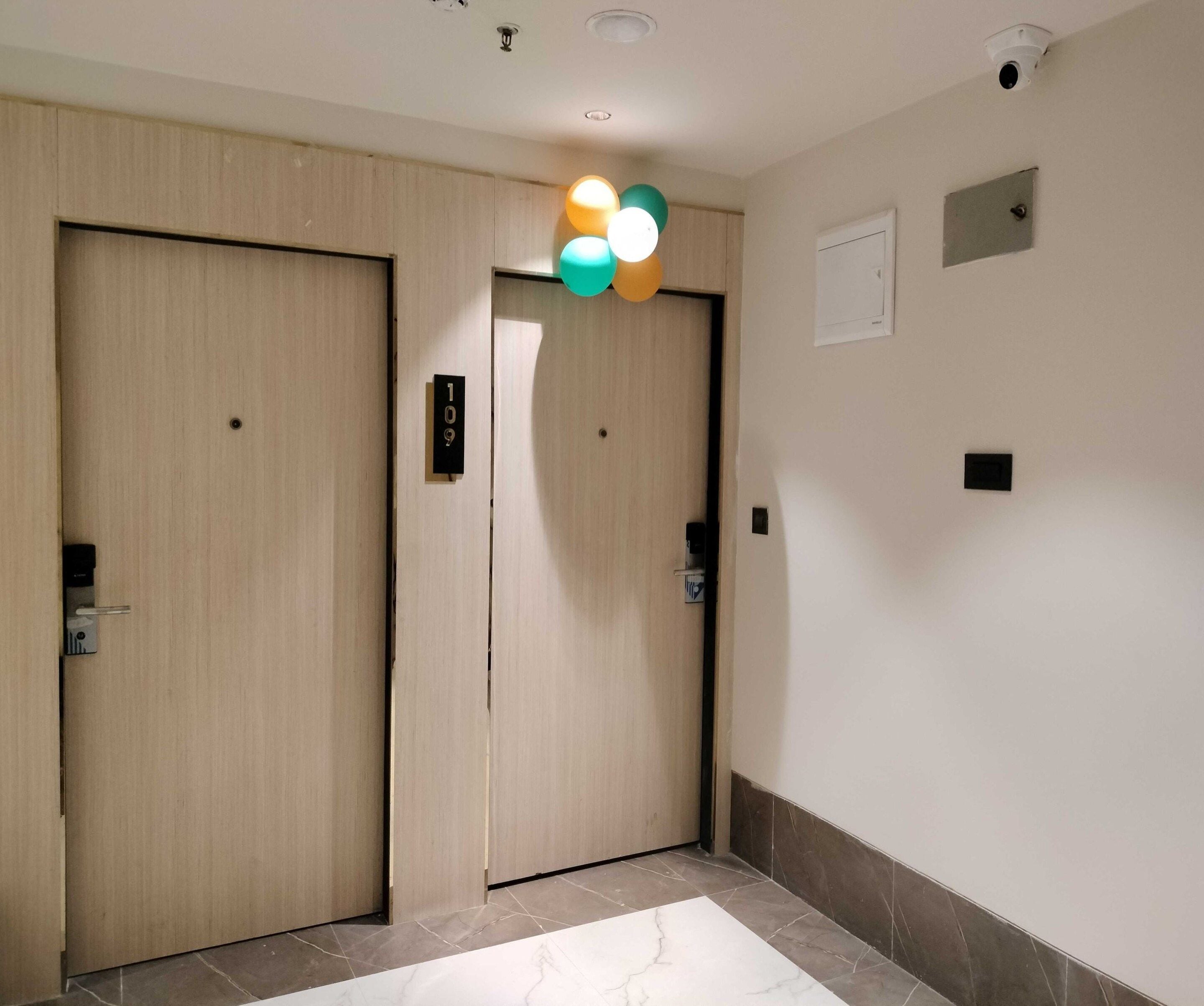 A hallway with two wooden doors, a marble floor, and a ceiling with recessed lighting.
