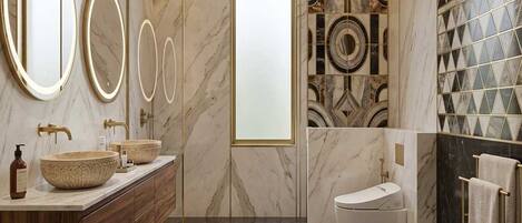 A modern bathroom with a marble vanity, dual sinks, and a freestanding toilet.
