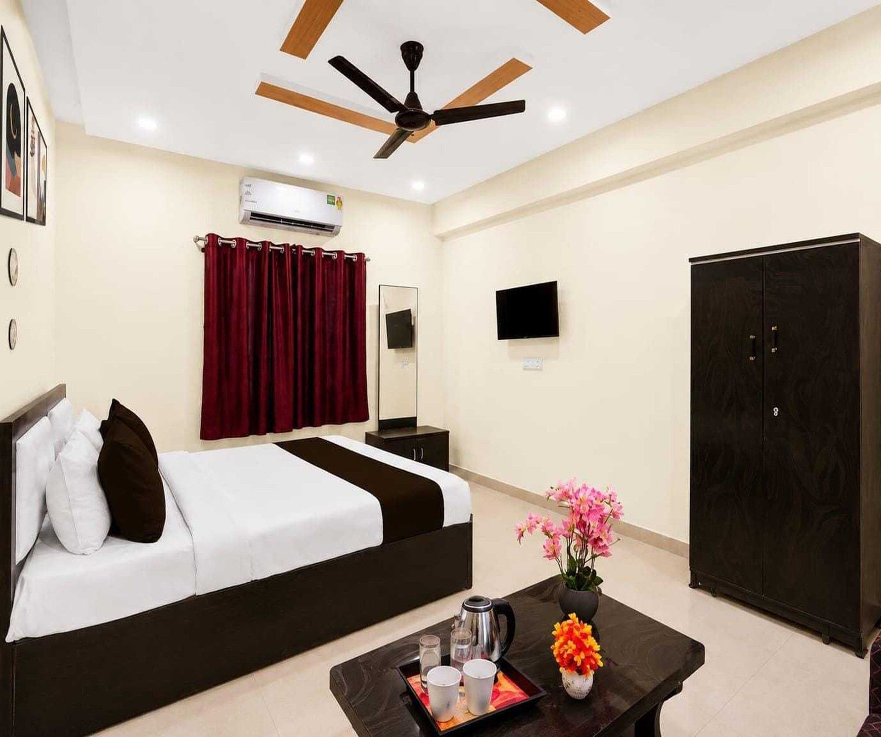 A hotel room with a bed, a coffee table with a tray, a TV, an air conditioner, and a wardrobe.