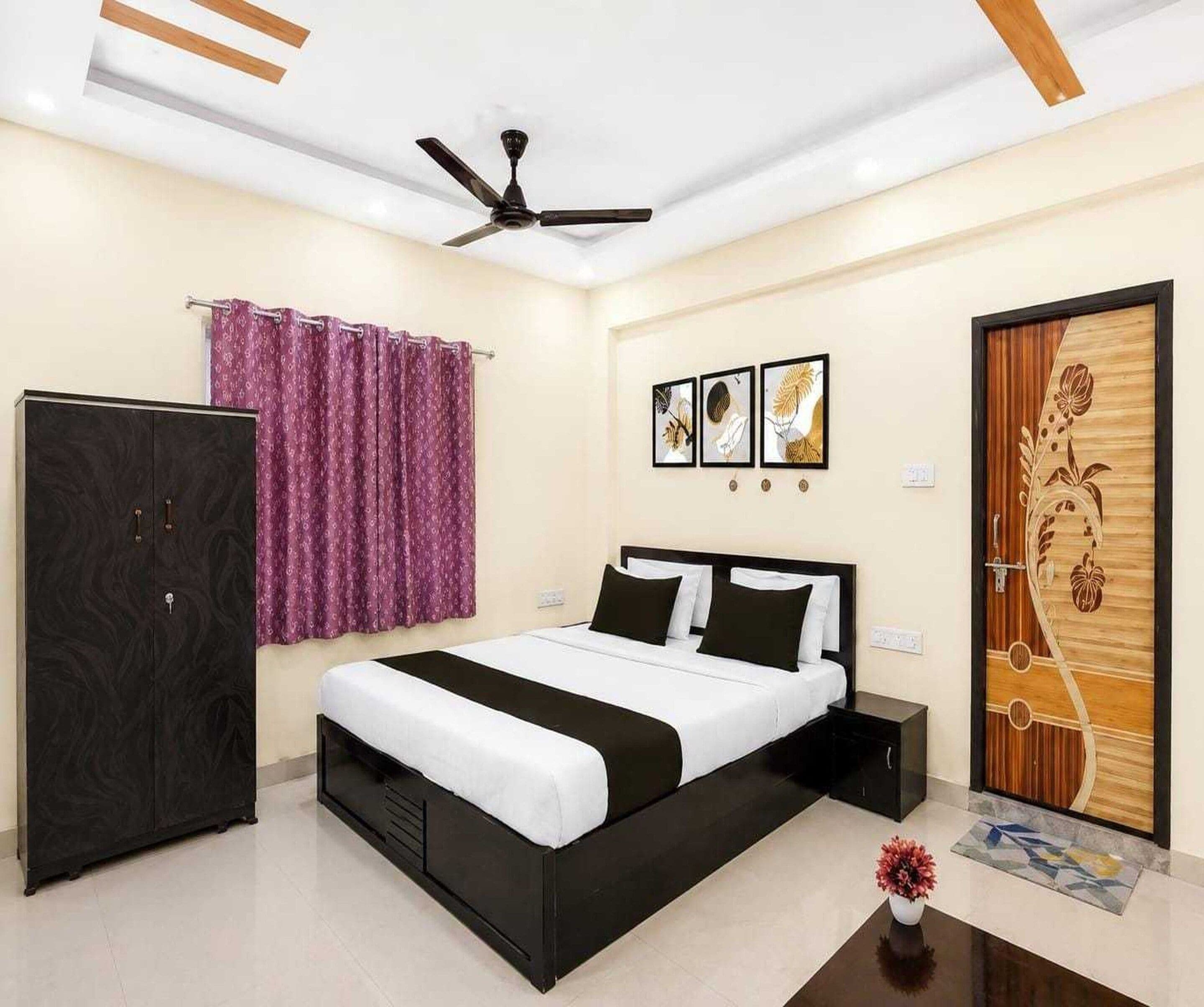 A bedroom with a bed, wardrobe, ceiling fan, and artwork on the wall.