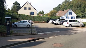 A parking area with cars, a solar-powered payment kiosk, and a residential building with a sloped roof. - La maison bleue (Saint-Valery-sur-Somme)
