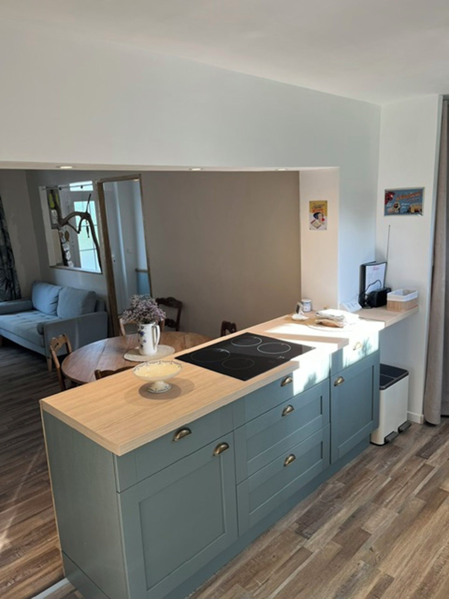 Une cuisine moderne dotée d’un îlot central, de revêtements de sol en bois et d’un coin repas avec un canapé et une table.