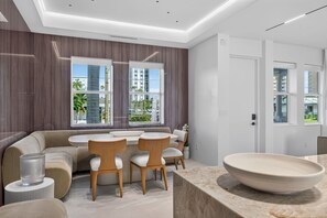Un intérieur moderne comprenant un coin salon, une table à manger et un grand saladier posé sur un comptoir.