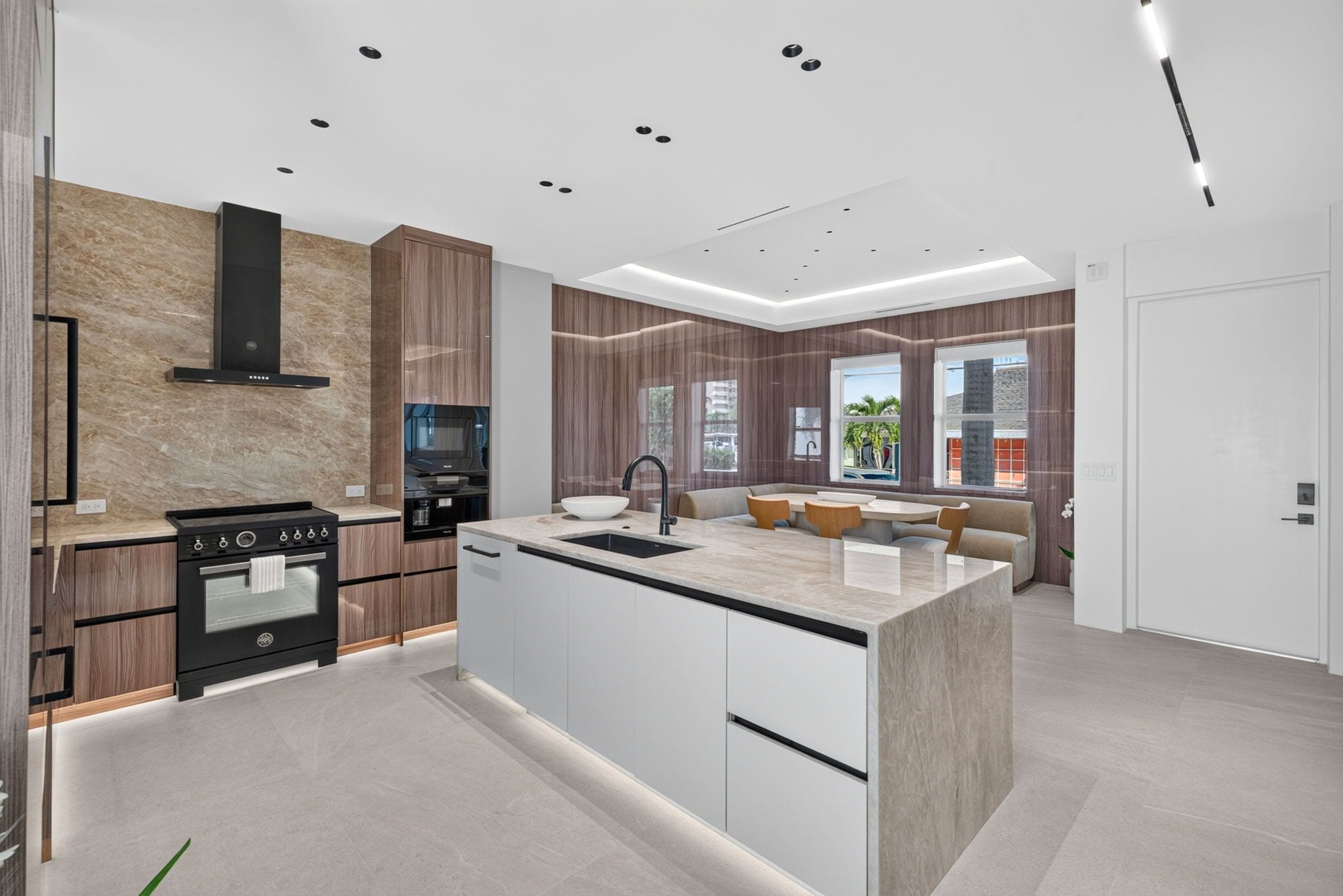 A modern kitchen with a central island, built-in oven, and a dining area with a sofa.