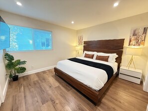 Ein Schlafzimmer mit einem hölzernen Bett, zwei Nachttischlampen, einem Topfpflanzen und einem Stadtbild an der Wand.