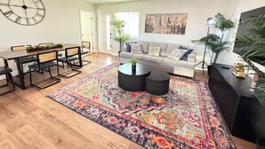 A modern living room with a dining area, a sofa, a coffee table, and a large wall clock. - West Adams 4 S Redondo (Los Angeles)