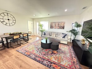 Ein modernes Wohnzimmer mit Essbereich, einer Couch, einem Couchtisch und einer großen Wanduhr.