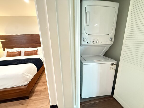 A hotel room with a bed, a washing machine, and a wooden headboard.