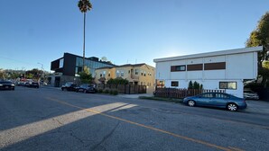 A street view with modern buildings, a palm tree, and parked cars. - West Adams 4 S Redondo (Los Angeles)
