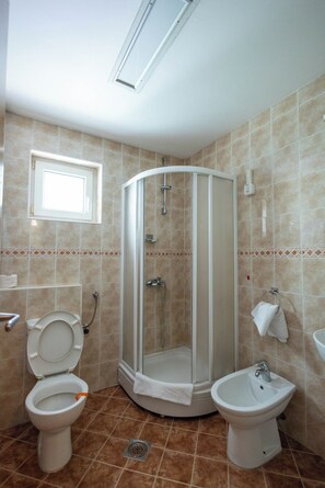 Un baño con ducha, inodoro, bidé y lavabo.