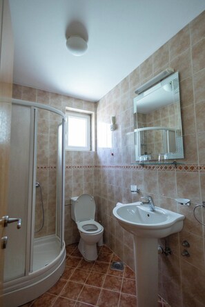 Une salle de bain avec douche, toilettes et lavabo.