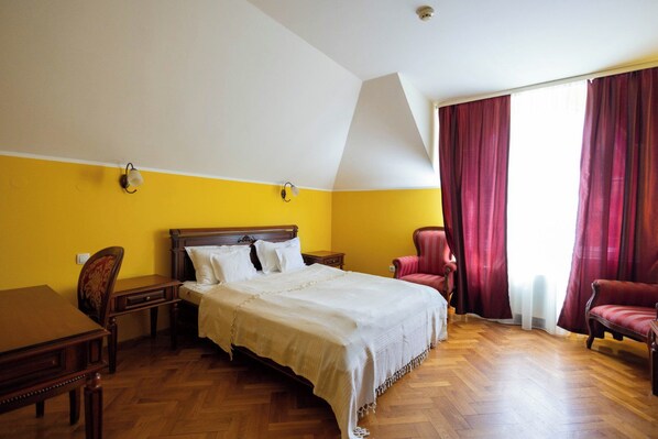 A hotel room with a bed, a desk, a chair, and a window with curtains.