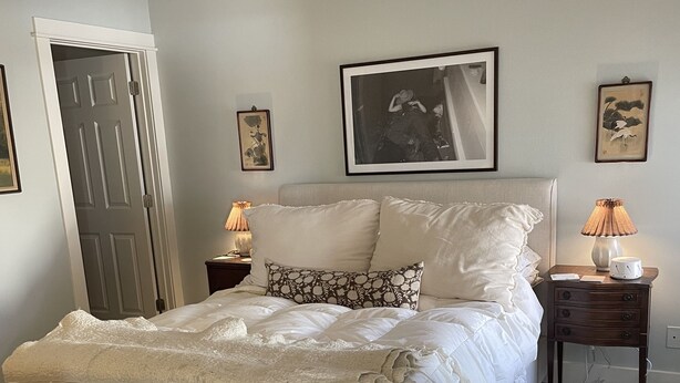 A bedroom with a bed, a nightstand, a lamp, and a door. - Two Bedroom Townhome With Trail Access (Bozeman)