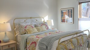 A bed with a metal frame, a bedside table with a lamp, and a rug on the floor. - Two Bedroom Townhome With Trail Access (Bozeman)