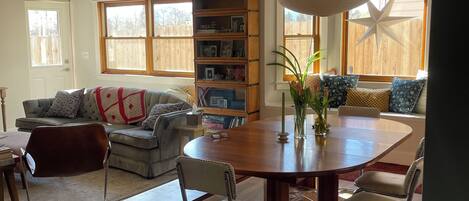 Un espacio habitable amplio con una mesa de comedor, sillas, una estantería y un ventanal grande.
