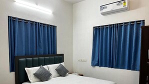 A bedroom with a bed, curtains, an air conditioning unit, and a nightstand. - Rivera Home | Lake View Homestay in Kadalundi (Balathiruthi)