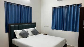 Ein Schlafzimmer mit Bett, Vorhängen, einer Klimaanlage und einem Nachttisch.