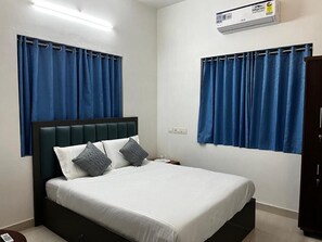 Ein Schlafzimmer mit Bett, Vorhängen, einer Klimaanlage und einem Nachttisch.