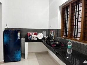 Eine moderne Küche mit schwarzem Arbeitsplatz, einem Kühlschrank, einem Herd und einem Fenster mit Gittermuster.
