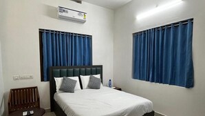 A hotel room with a bed, a chair, a table, and curtains. - Rivera Home | Lake View Homestay in Kadalundi (Balathiruthi)