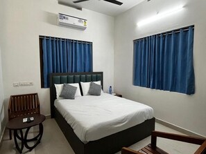 Ein Hotelzimmer mit Bett, Stuhl, Tisch und Vorhängen.