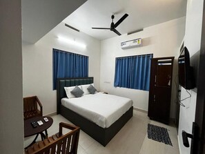 Ein Schlafzimmer mit Bett, Schreibtisch, Stuhl, Deckenventilator und Fernseher.