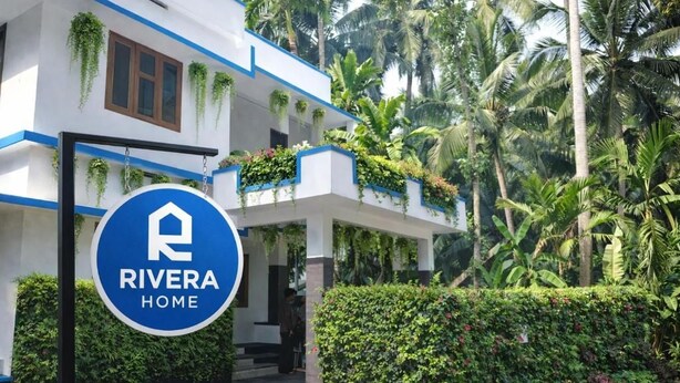 A hotel entrance with a sign reading 'RIVERA HOME,' surrounded by lush greenery and palm trees. - Rivera Home | Lake View Homestay in Kadalundi (Balathiruthi)