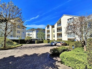 Ein Mehrfamilienhaus mit befestigter Auffahrt und parkenden Autos.