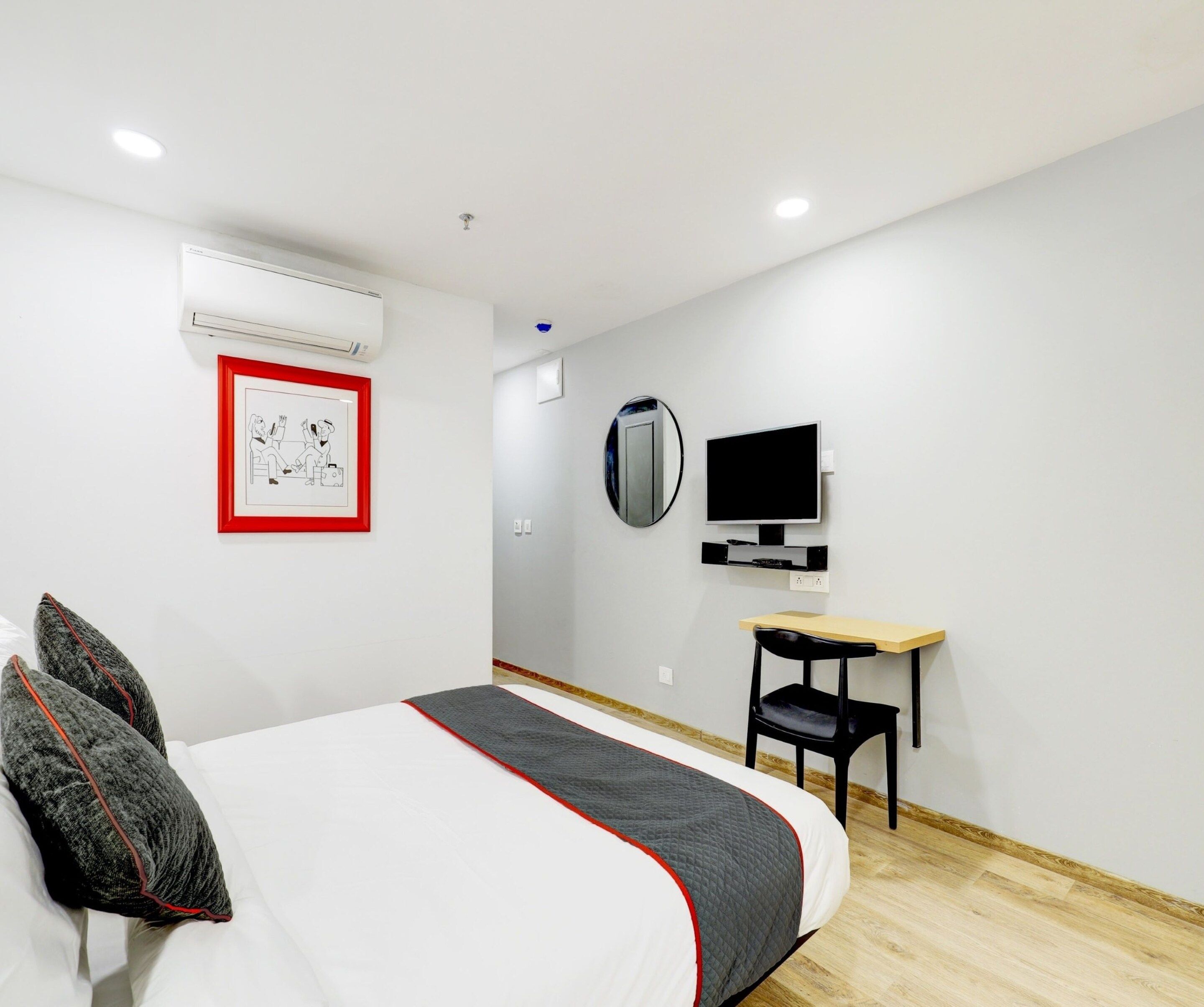 Una habitación de hotel con cama, escritorio, televisión y aire acondicionado.