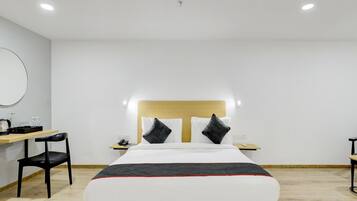 Une chambre d’hôtel avec un lit, des tables de chevet, un bureau et une chaise.