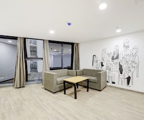 A modern room with a sofa, a small table, and a wall mural depicting a group of people.