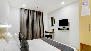 Een hotelkamer met een bed, een bureau, een televisie en een kledingkast.
