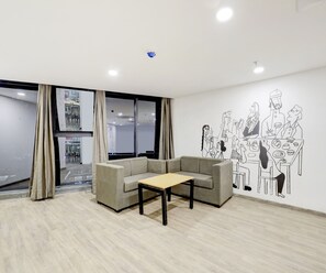 A modern office space with a sofa, a small table, and a large window with curtains.