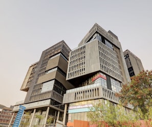 A multi-story building with a modern architectural design, featuring a mix of glass and concrete facades, and a prominent signage for a gym. - Super Deluxe Room Hotel Rajyash Rise (Ahmedabad)
